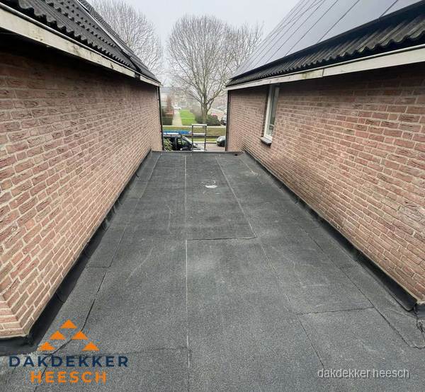 Plat dak met bitumen dakbedekking tussen bakstenen muren in Heesch Plat dak met bitumen dakbedekking tussen bakstenen muren in Heesch